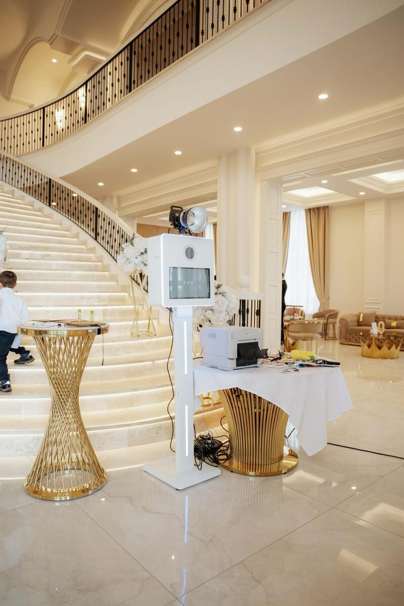 Cabina foto albă cu lumină de studio și imprimantă, montată într-un salon elegant de evenimente