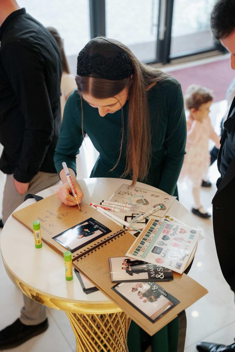 Invitată care scrie un mesaj în guestbook-ul cu fotografii de la nuntă
